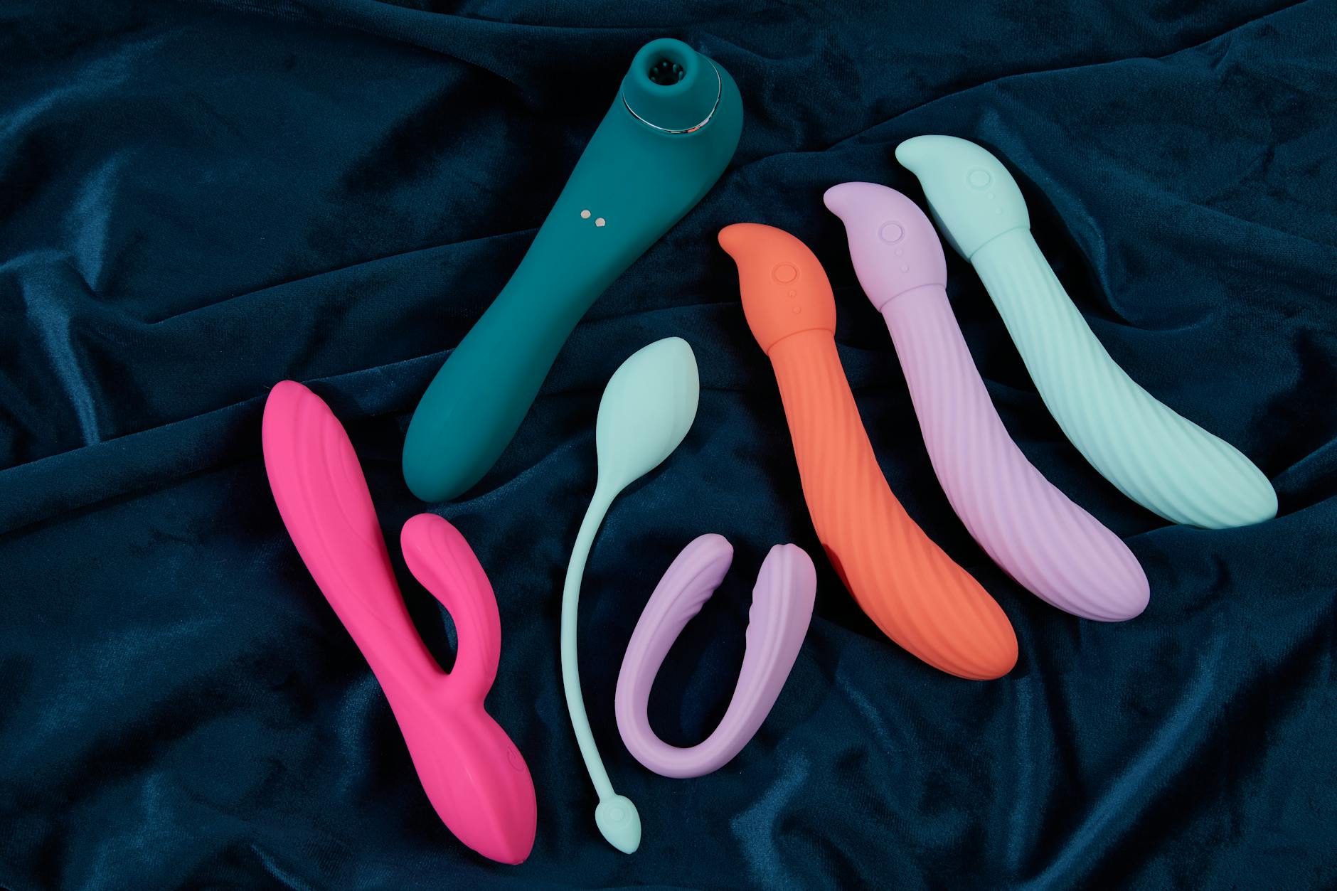 Vibrant display of silicone clitoral vibrators on dark fabric