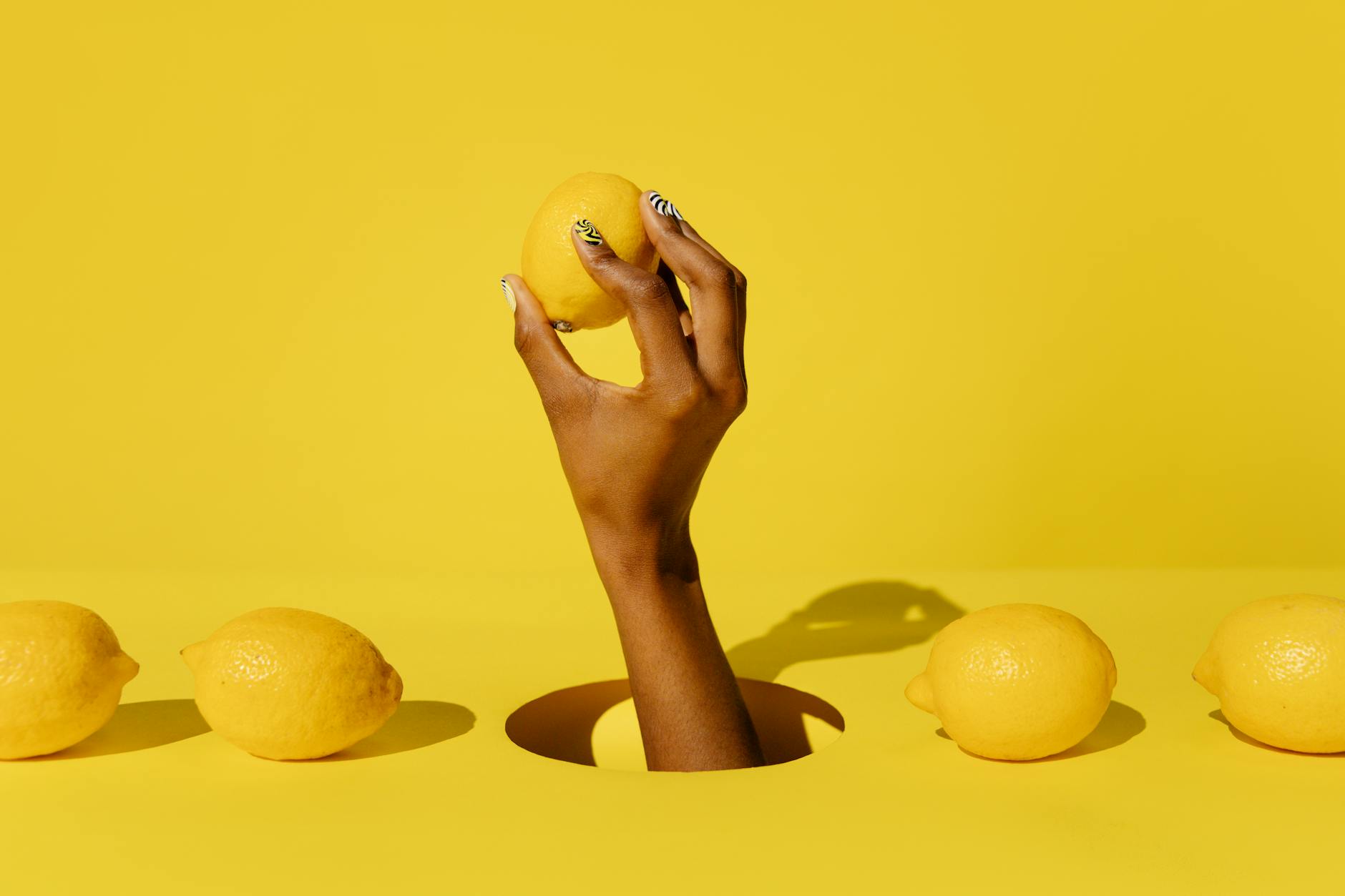 Hand holding a lemon against a vivid yellow background, symbolizing fresh perspectives on desire and frequency