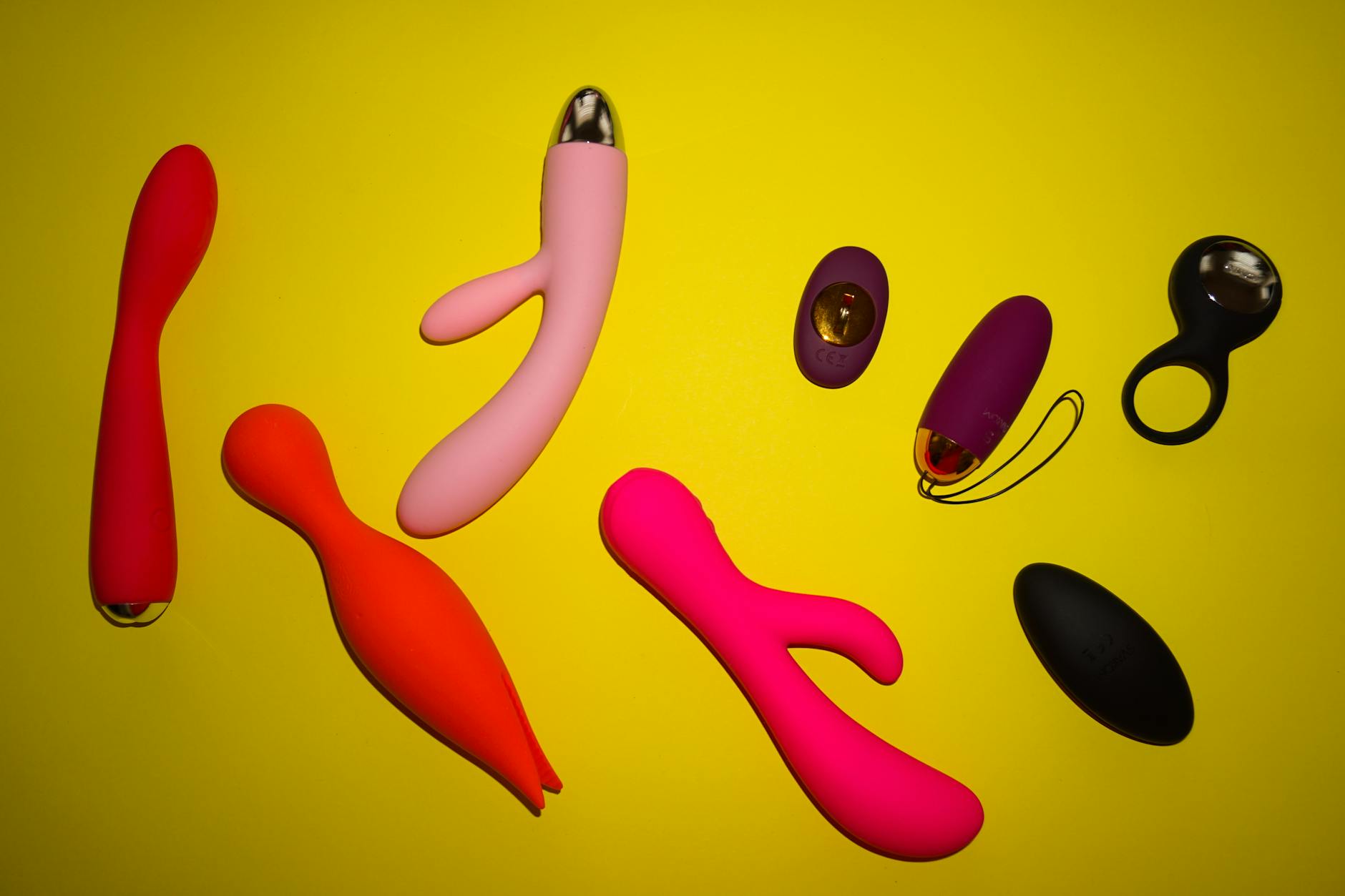 Woman holding colorful vibrators, considering her pleasure in partnered intimate moments