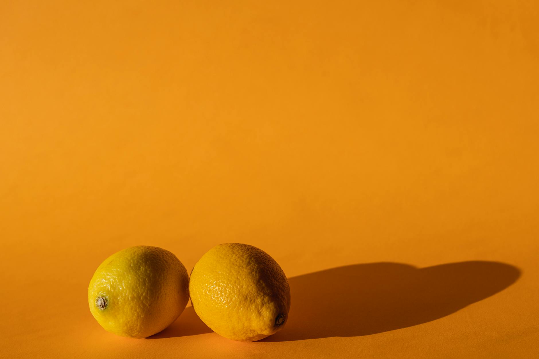 Fresh ripe lemons on a bright yellow background, representing the bright energy of Hello Nancy lemon vibrators